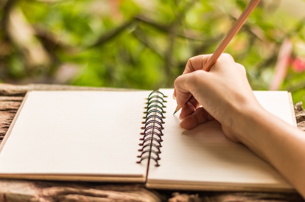 Woman writing in a birdwatching notebook.